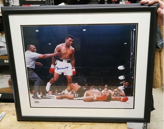 Picture of " MUHAMMAD ALI KNOCKS OUT SUNNY LISTON" . AUTOGRAPHED. FRAME SIZE 22X25 . PICTURE SIZE 19X22. WITH GRANDSTAND SPORT HOLOGRAM, ONLINE AUTHENTIC HOLOGRAM .